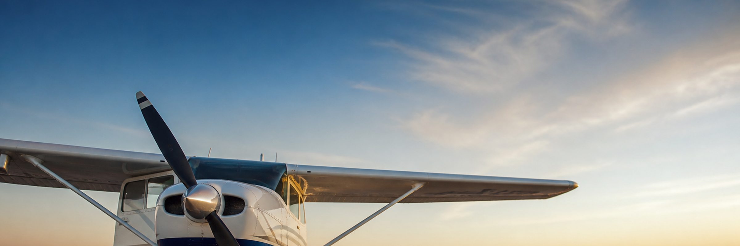 Single-engine aircraft on an airport ramp at sunset